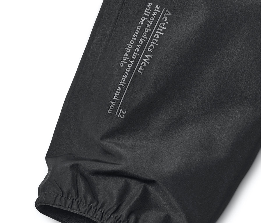 Gros plan sur une veste coupe-vent noire avec l'inscription Aéthletics Wear.