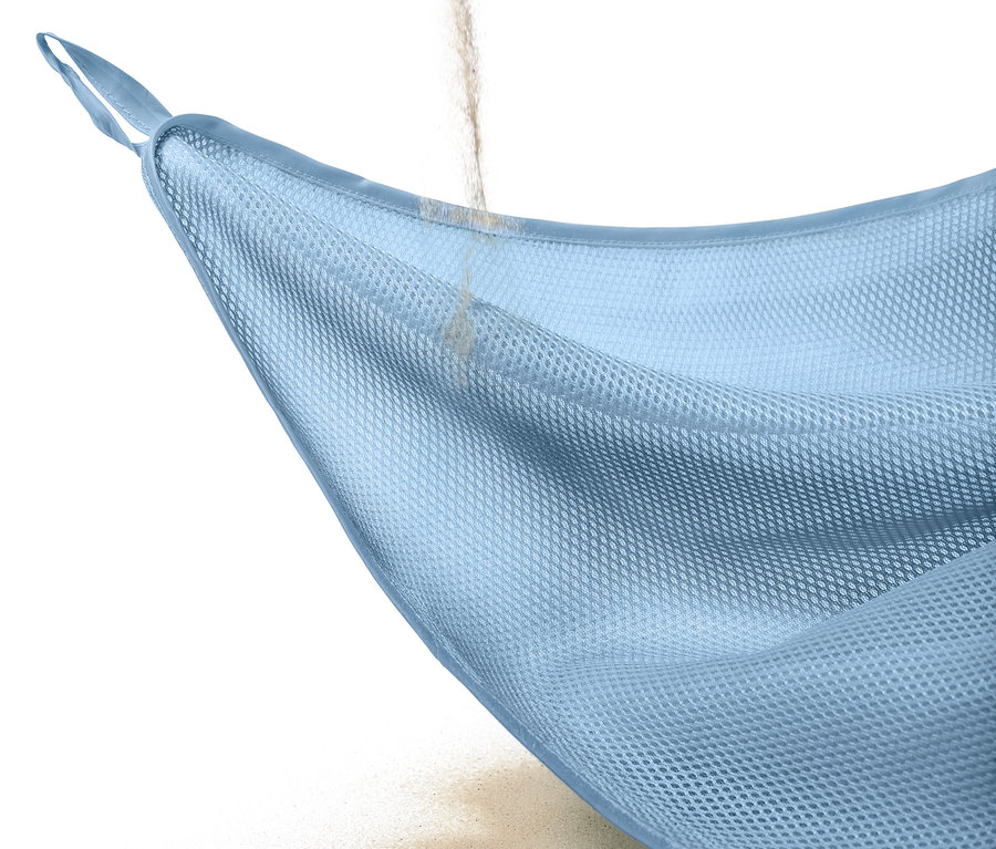 Du sable tombe à travers une couverture de plage anti-sable.