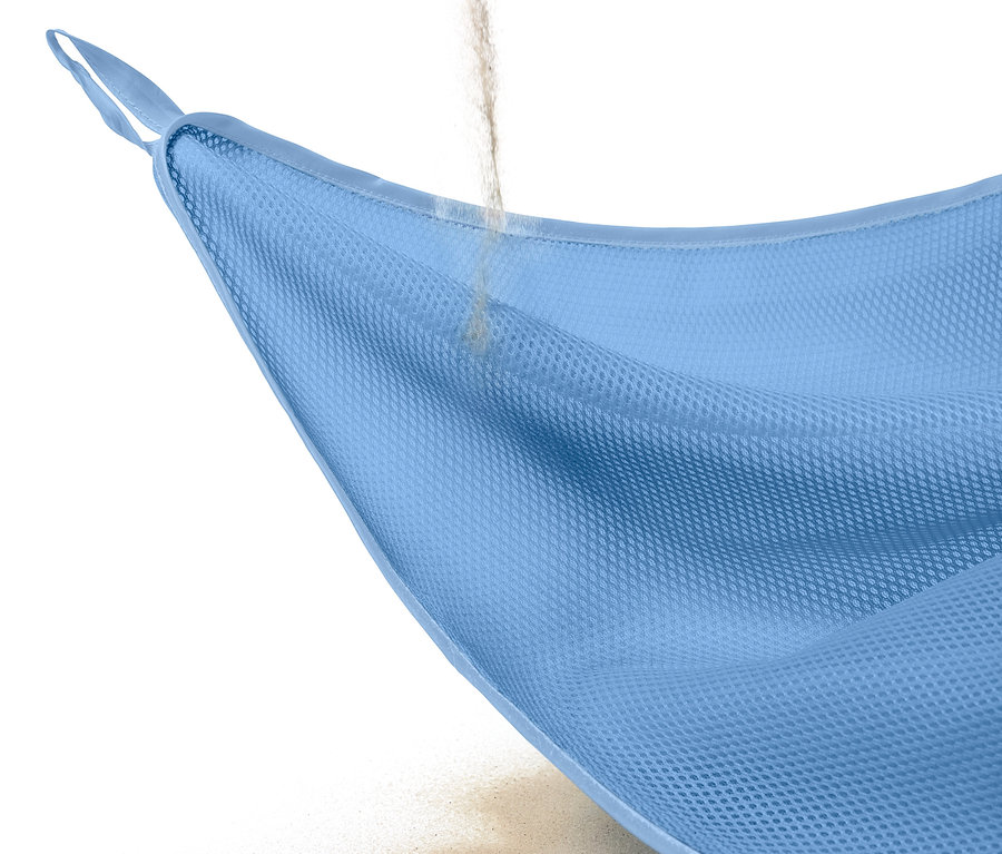 Du sable coule à travers une couverture de plage anti-sable bleu clair.