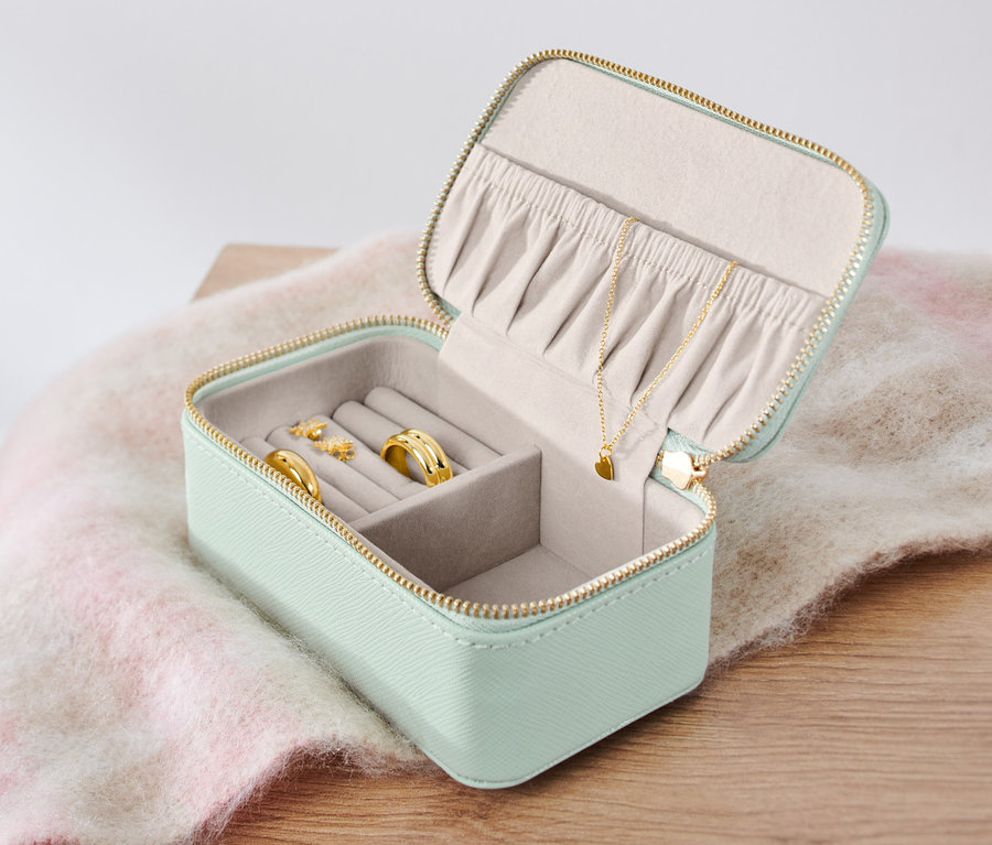 Petite boîte à bijoux ouverte avec des bagues, des boucles d'oreilles et un collier.