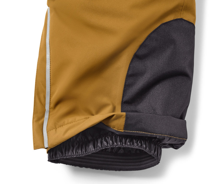 Détail d'un pantalon de ski pour enfant, camel, avec tissu noir et bande réfléchissante.