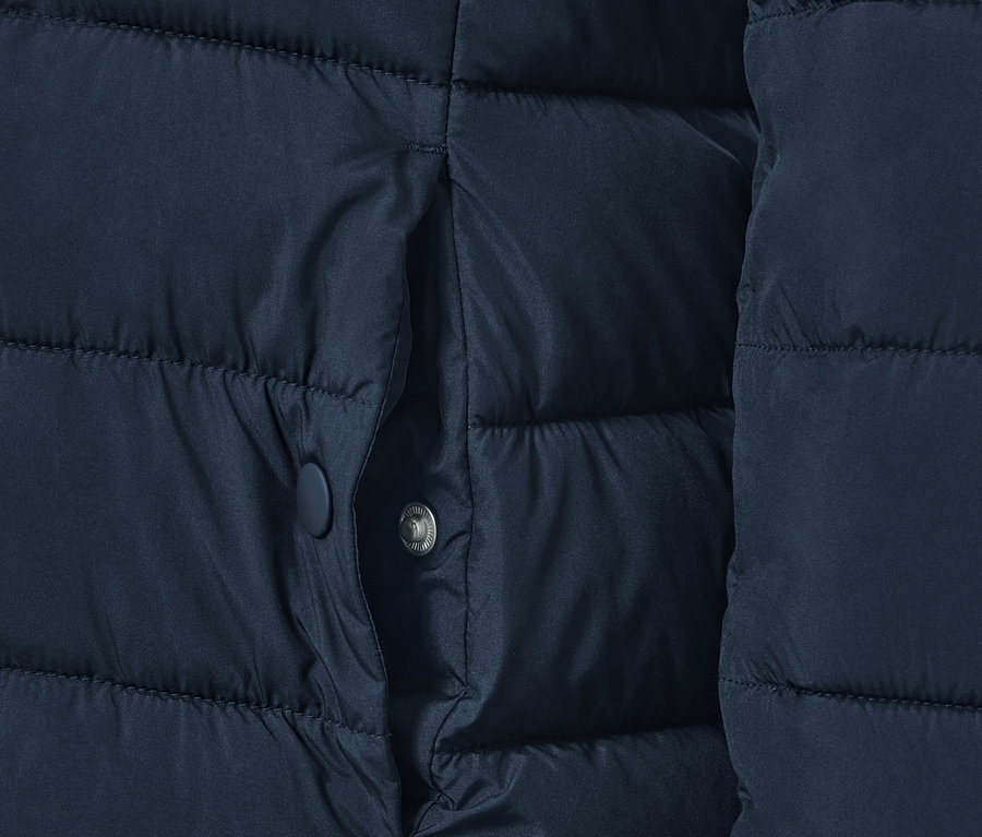 Détail d'une veste matelassée bleu foncé avec une poche.