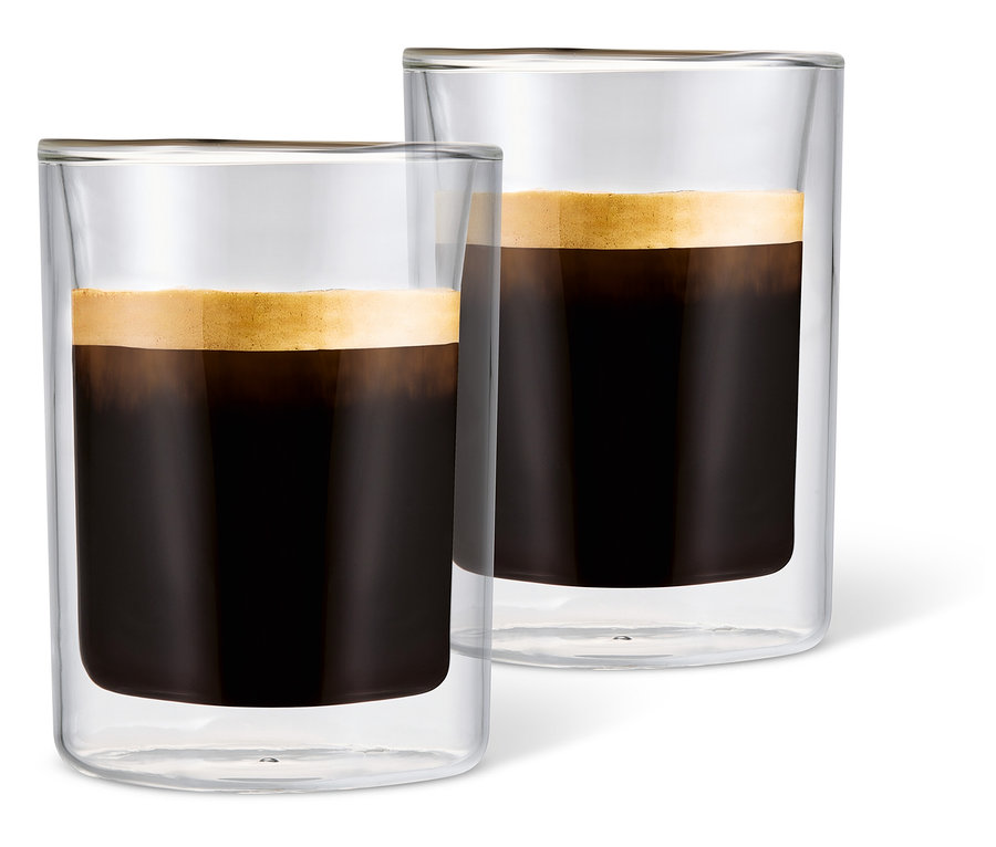 Deux verres à café crème remplis de café avec de la mousse sur fond blanc.