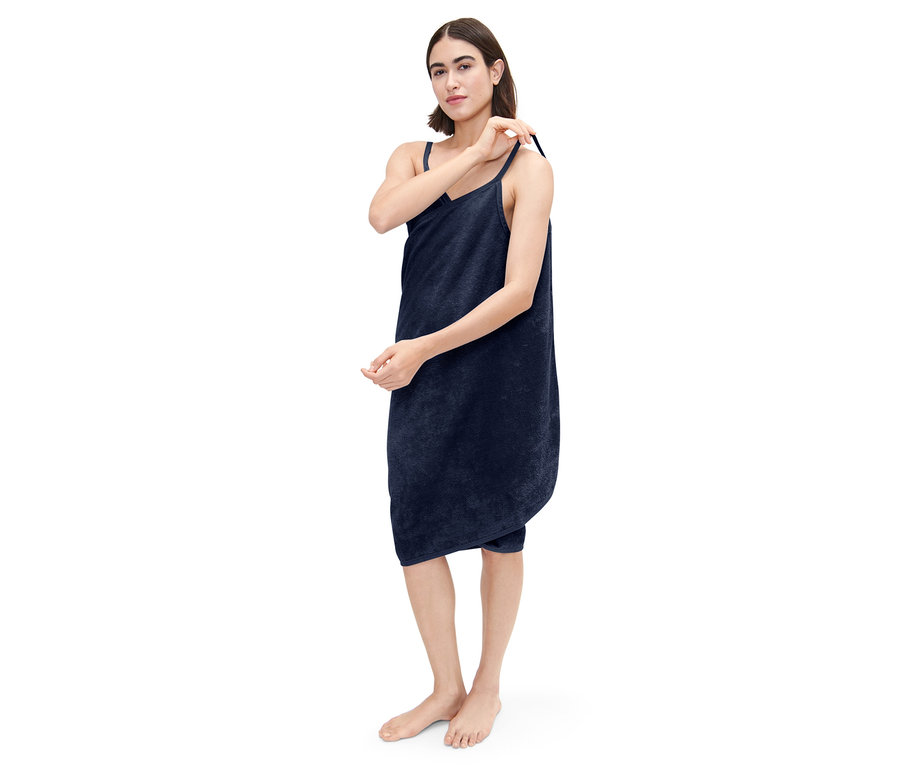Femme ajustant la bretelle d'une robe-linge de toilette bleu foncé.