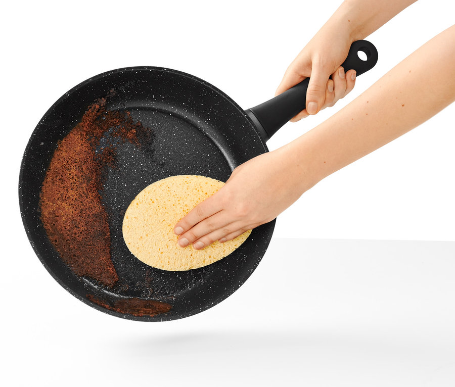 Une poêle professionnelle de 28 cm d'aspect pierre est nettoyée avec une éponge.