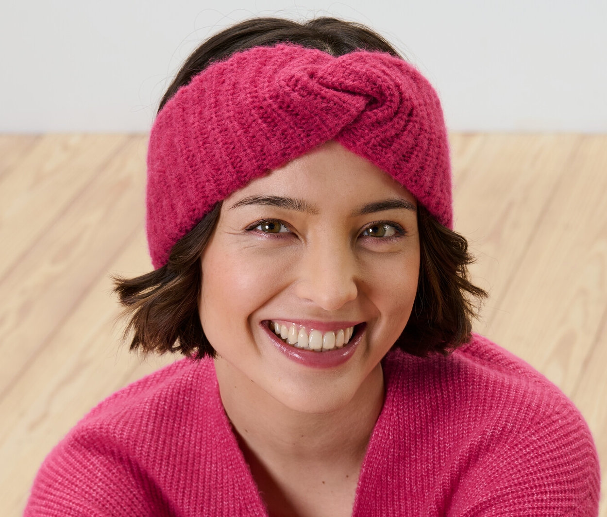 Une femme souriante portant un bandeau rose.
