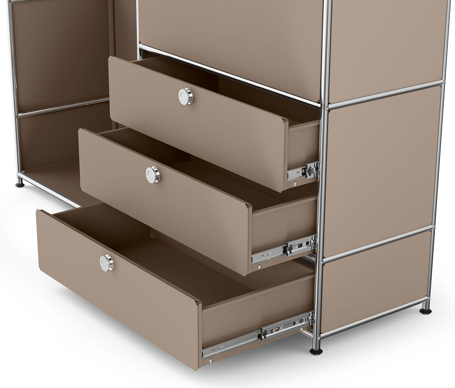 Gros plan sur la commode en métal « CN3 » avec plateau en bois et trois tiroirs ouverts en taupe.