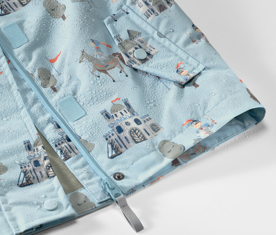 Gros plan sur une veste de pluie pour enfant à motif de chevalier, avec des gouttes d'eau dessus.