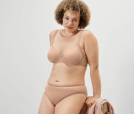 Une femme pose en soutien-gorge à armatures et culotte couleur chair.