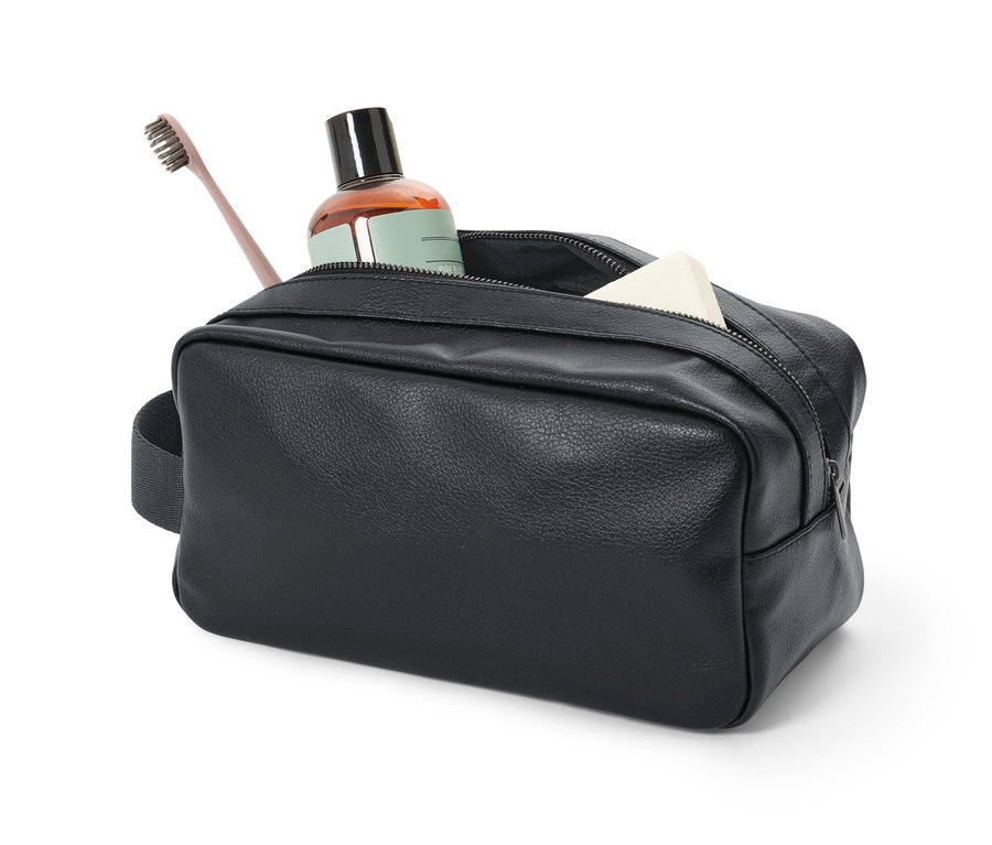 Une trousse de toilette noire avec une bouteille marron, une brosse à dents et du savon.