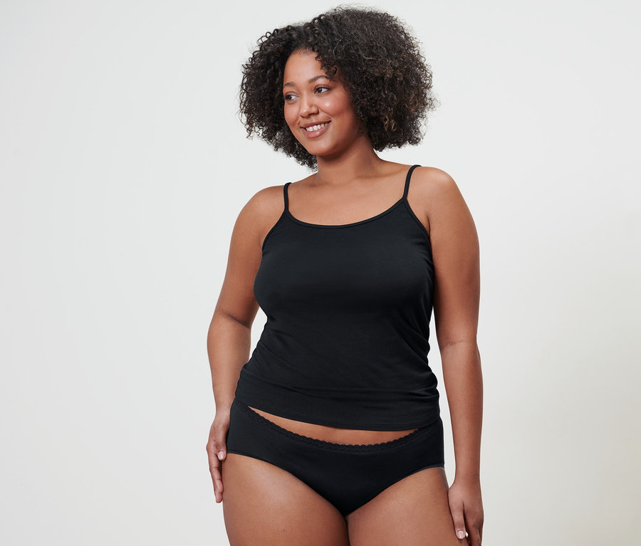 Une femme porte 5 culottes noires et une chemisette spaghetti.