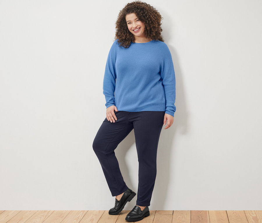 Femme posant en pull en maille bleu et pantalon de jogging bleu marine.