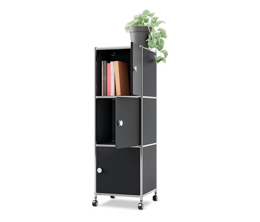 Caisson en métal à roulettes « CN3 » noir avec 3 portes. Une plante est posée dessus, la porte supérieure est ouverte et révèle des livres, la porte du milieu est également ouverte.