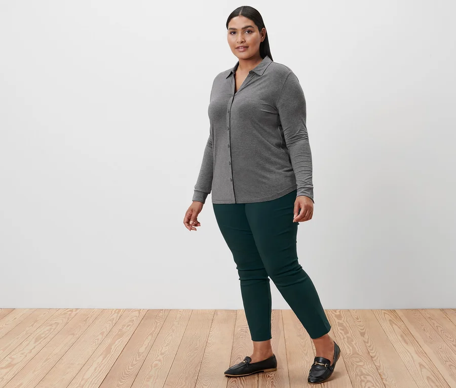 Femme qui marche et porte une blouse avec patte de boutonnage grise chinée, un pantalon stretch et des mocassins en cuir.
