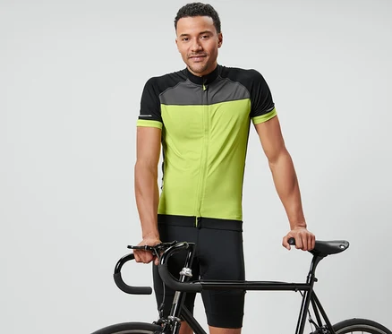 Un homme pose avec un vélo et porte un maillot de cyclisme.