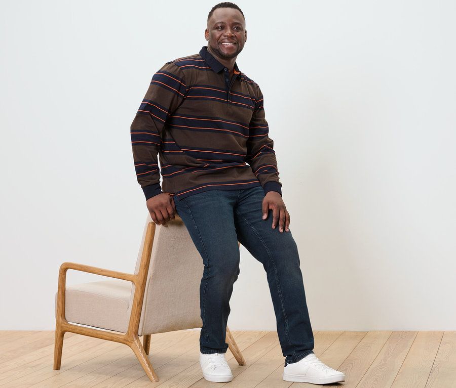 Un homme est assis sur une chaise et porte un polo à manches longues.