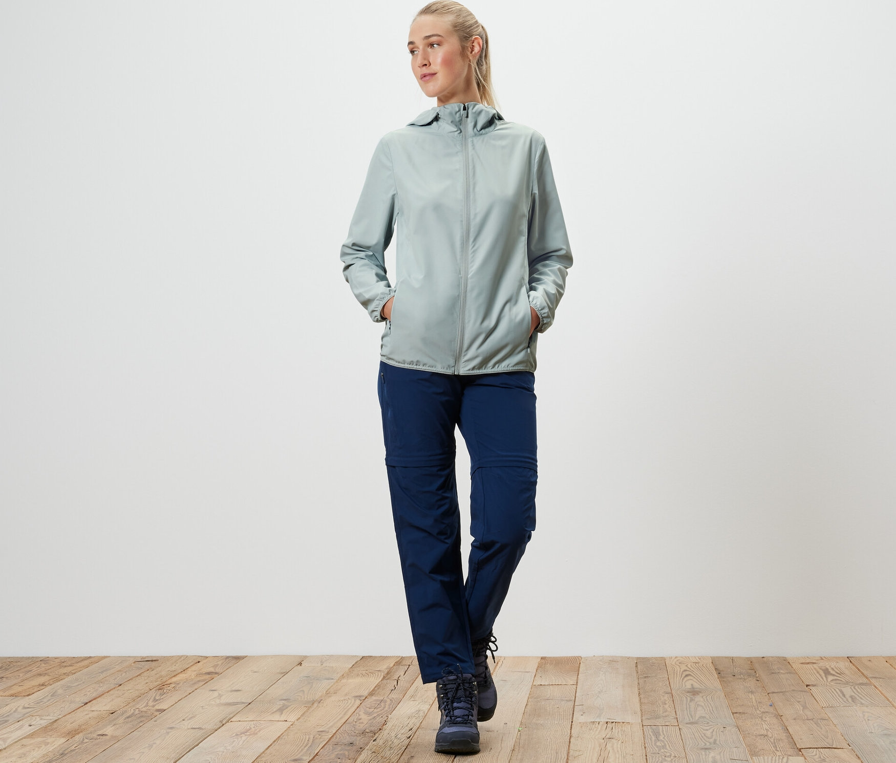 Une femme marche et porte une veste fonctionnelle pliable grise.