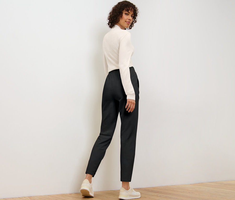 Femme posant par-dessus son épaule en pantalon de jogging noir.