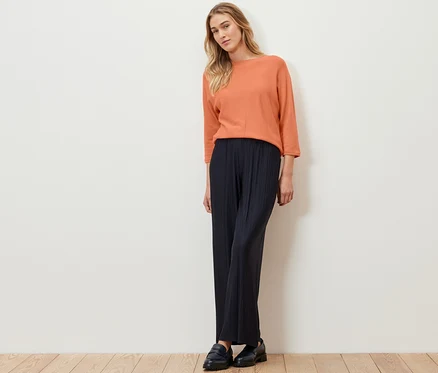 Une femme debout portant un pull en maille fine de laine mérinos pêche.