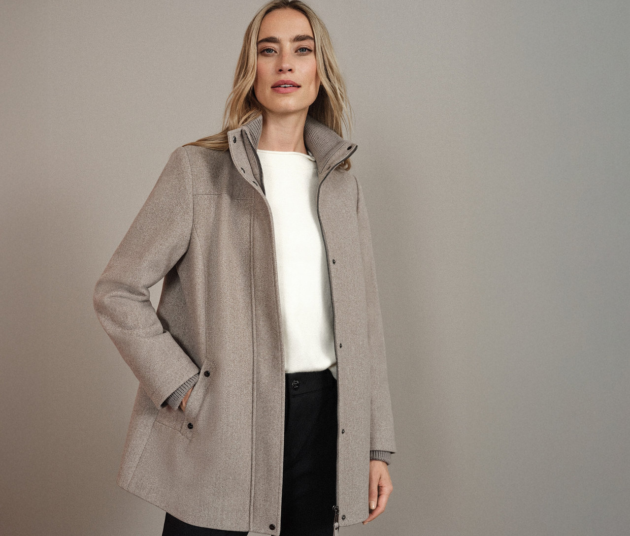 Femme portant un manteau court Street One beige, combiné avec un haut blanc et un pantalon noir.