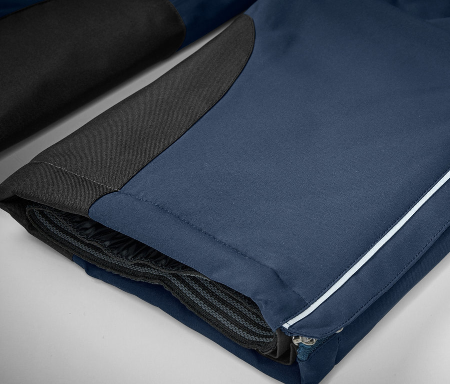 Détail d'un pantalon bleu avec des détails noirs et une bande blanche.