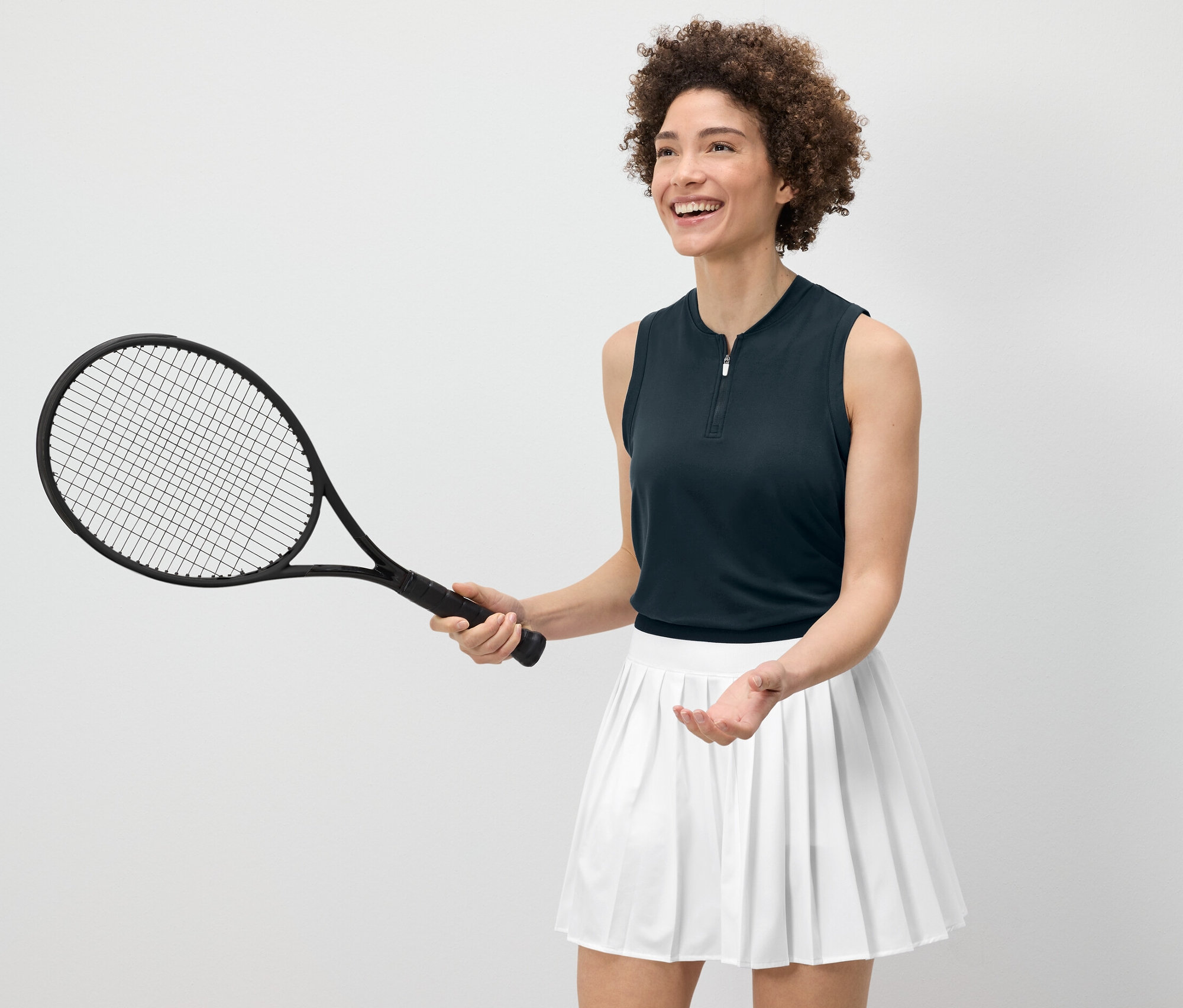 Femme tenant une raquette de tennis et portant un top fonctionnel bleu foncé.