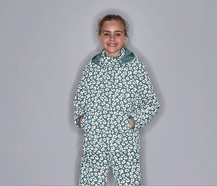Une fille pose dans une veste de pluie thermique avec des éléments réfléchissants et un motif léopard.