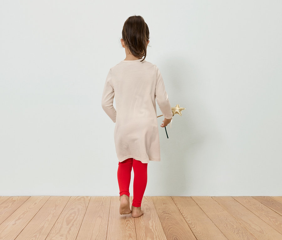 Une fille en robe et leggings tient une étoile à la main, dos à la caméra.