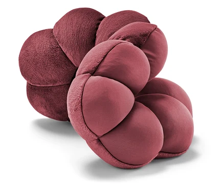 Gros plan d'un coussin bordeaux en forme de fleur.
