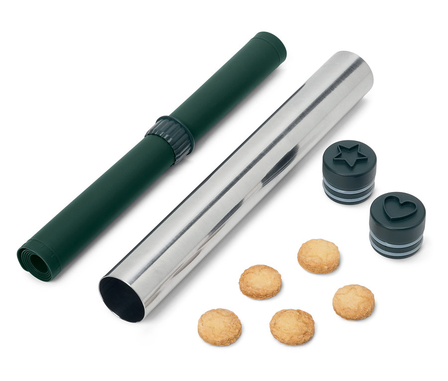 Un tapis de roulement vert et un rouleau à pâtisserie argenté avec des emporte-pièces en forme d'étoile et de cœur et des biscuits.