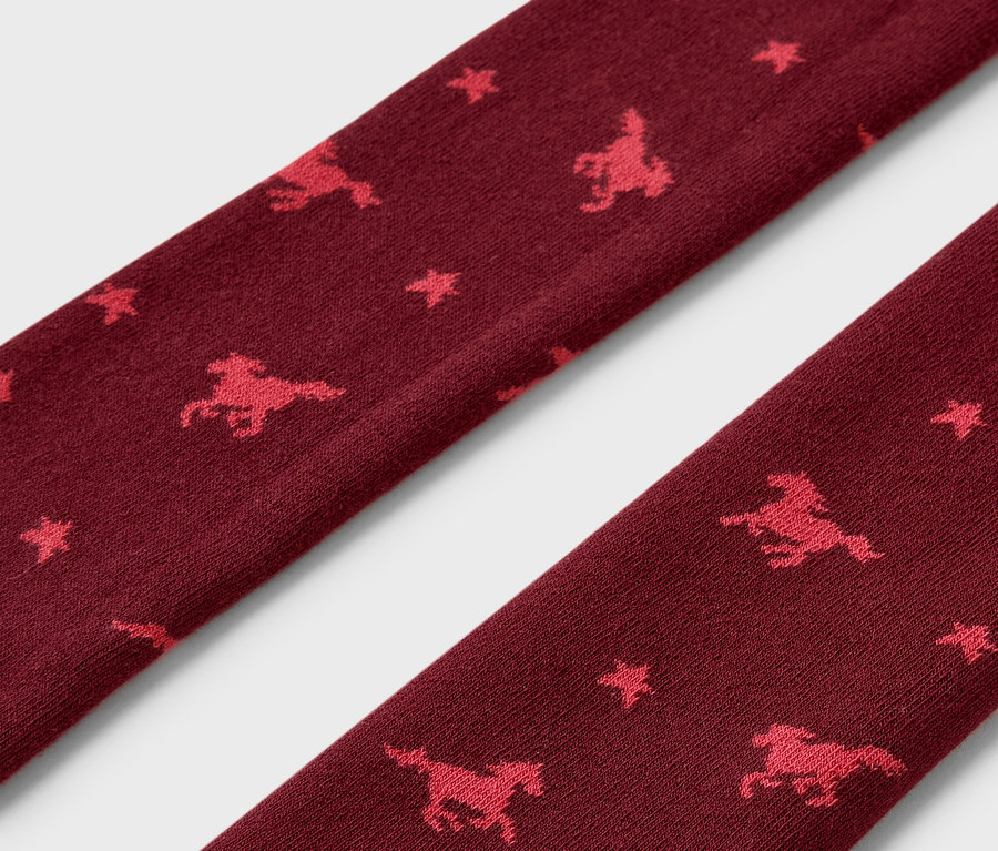 Gros plan sur des leggings thermiques bordeaux avec motif de chevaux et d'étoiles.