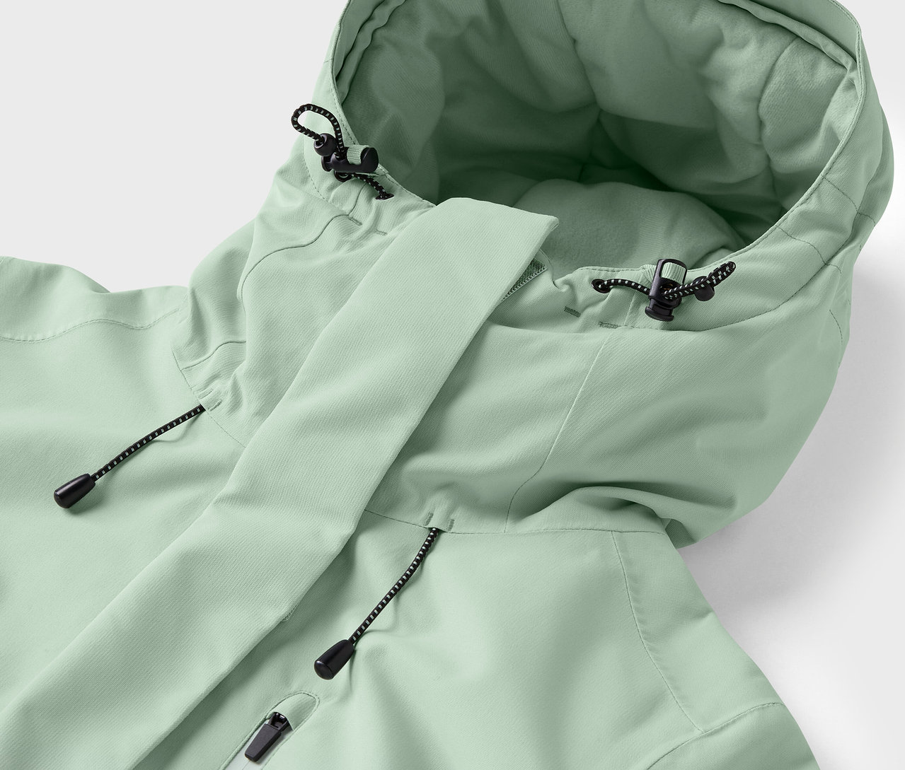 Gros plan sur une veste vert clair avec capuche et cordons de serrage.