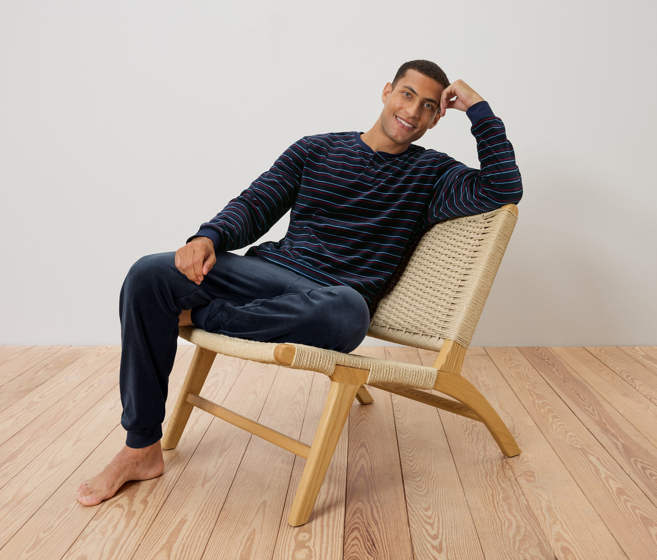 Un homme est assis sur une chaise en pyjama rayé.
