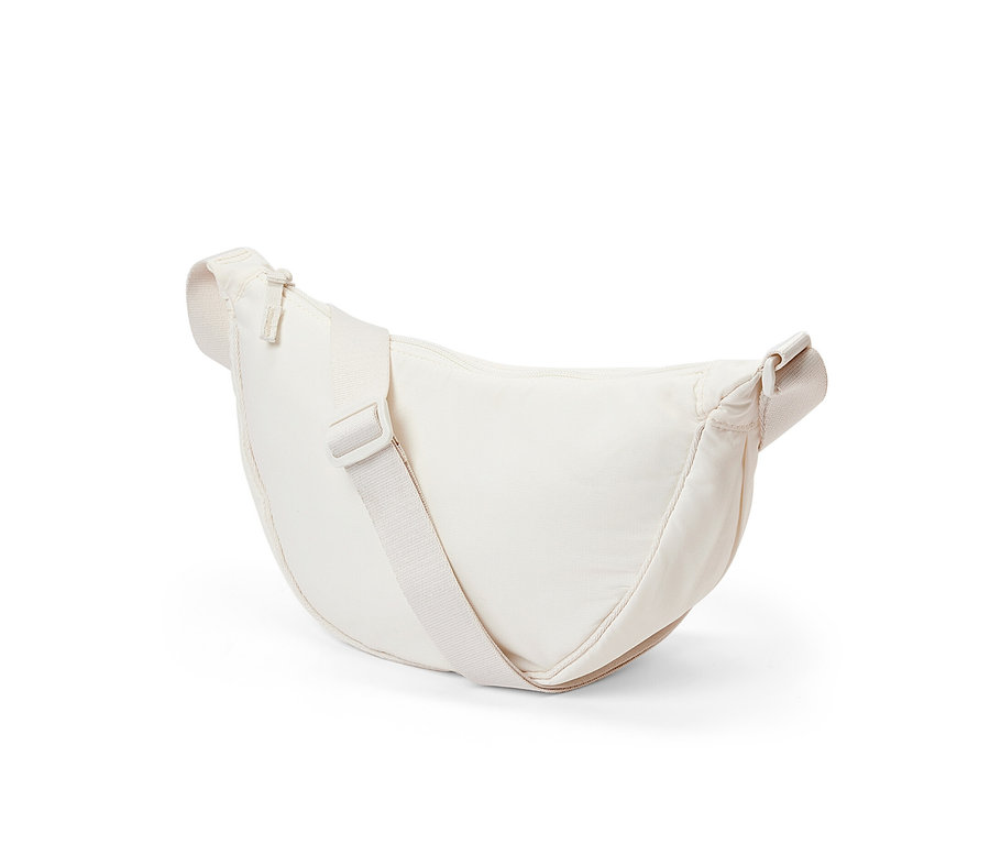 Un sac à bandoulière crème est posé sur un fond blanc.