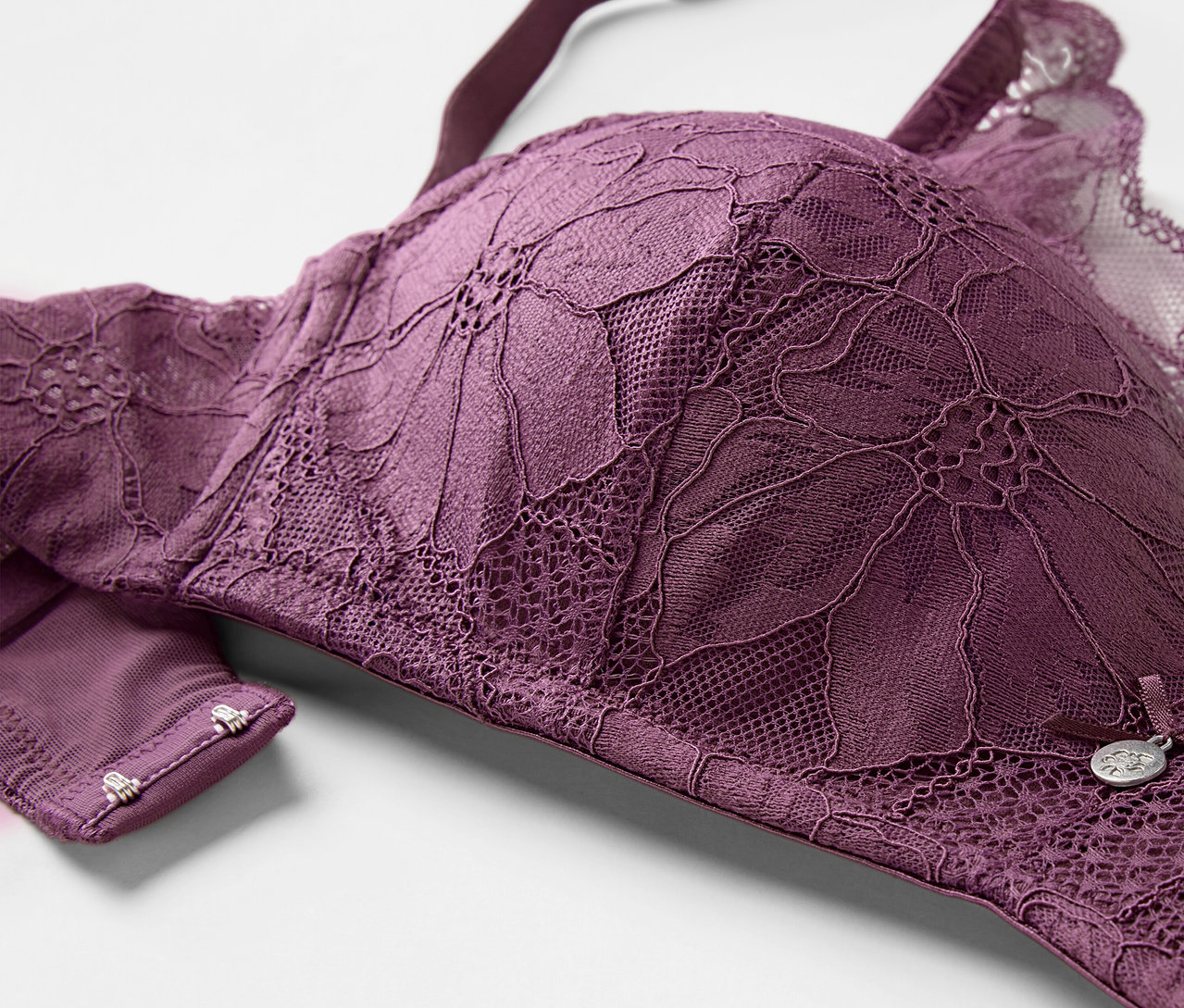 Détail d'un soutien-gorge à coques souples aubergine avec de la dentelle florale.