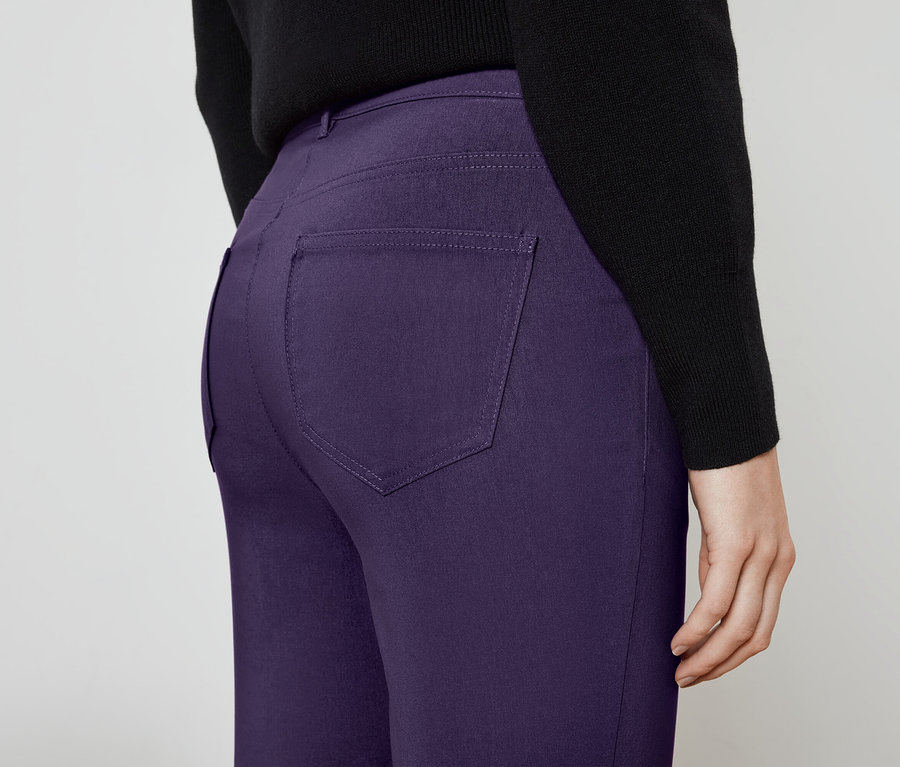 Gros plan de l'arrière d'un pantalon violet porté par une personne portant un pull noir.