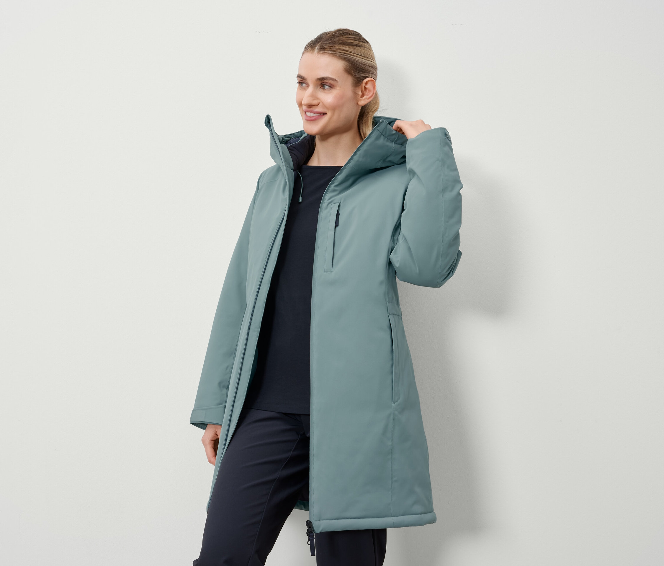 Une femme porte un long manteau pétrole.