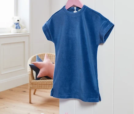 Une robe stretch en velours côtelé bleue est suspendue à un cintre rose.