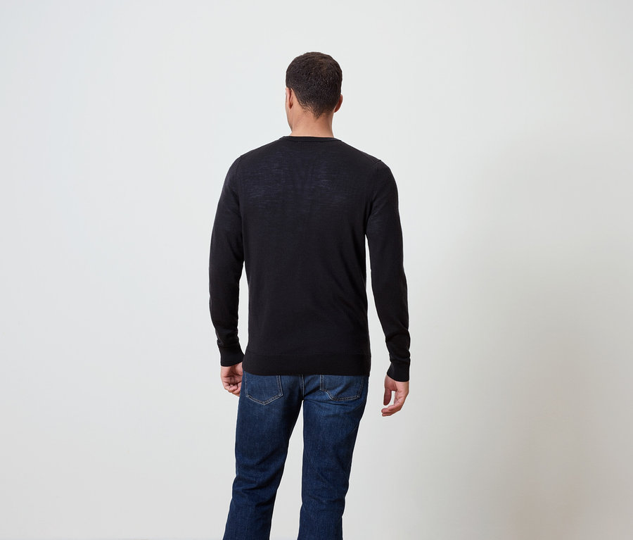 Homme de dos portant un pull foncé et un jean.