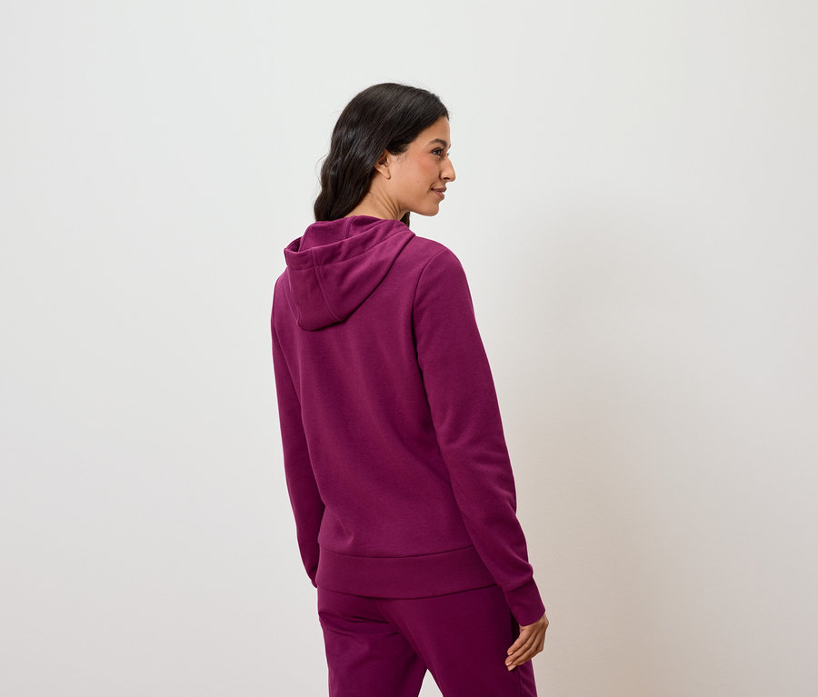 Femme posant dans un sweat à capuche violet et un pantalon.
