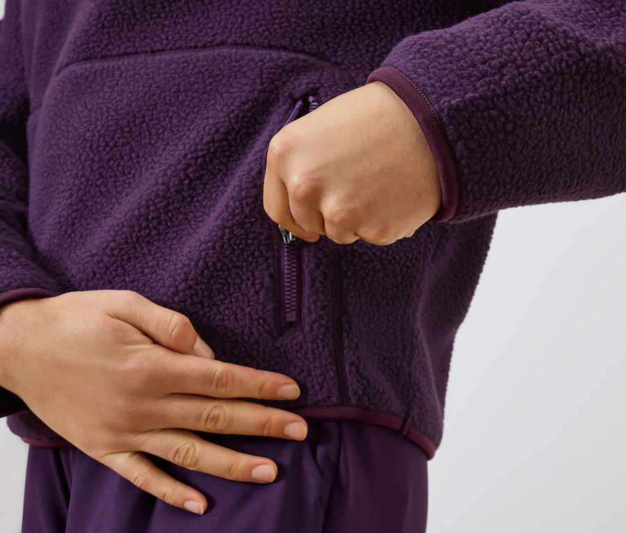 Une personne ferme la fermeture éclair d'un pull en laine violet.