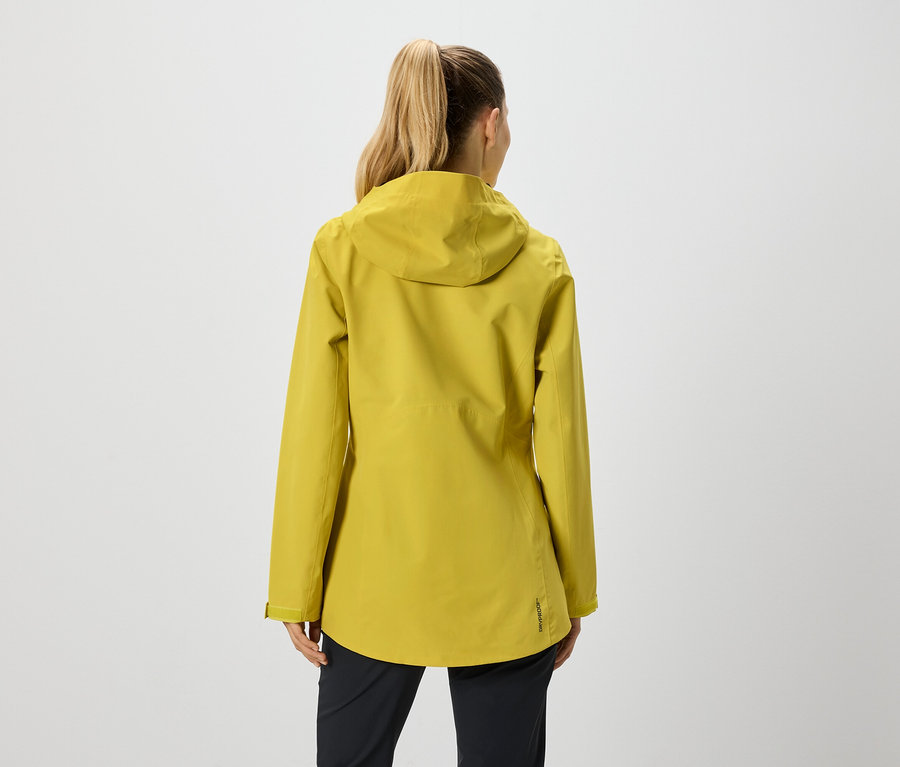 Vue arrière d'une femme avec une queue de cheval portant une veste jaune moutarde à capuche et un pantalon noir.