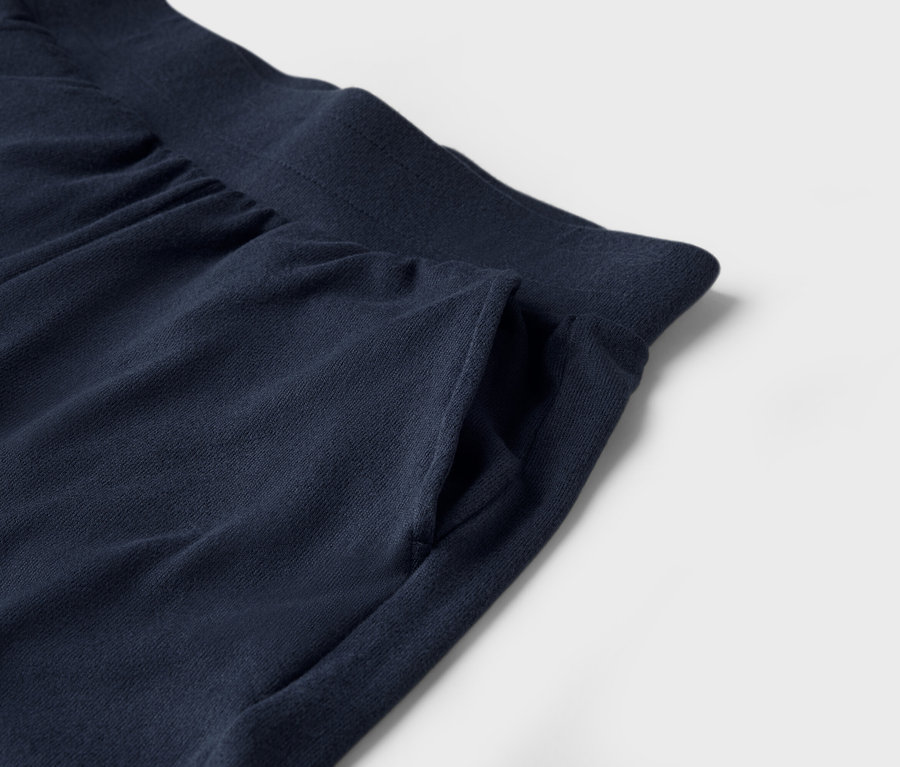 Gros plan d'un pantalon de jogging bleu marine avec une poche sur fond blanc.