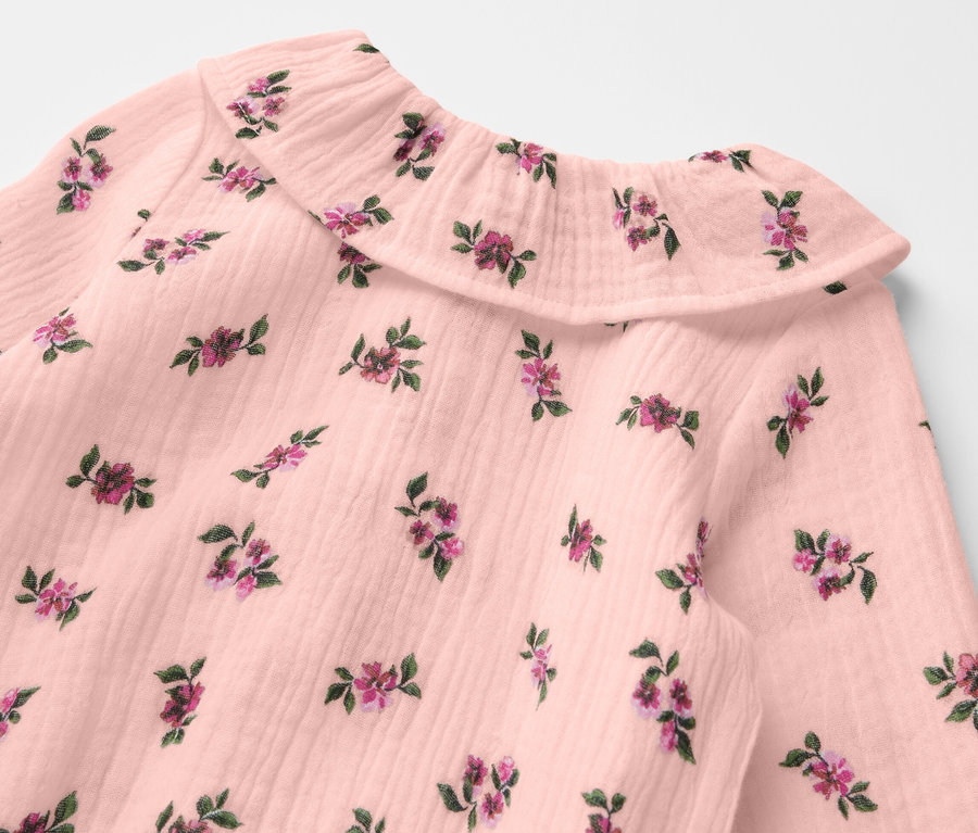 Détail d'un body en mousseline pour bébé avec un motif floral.