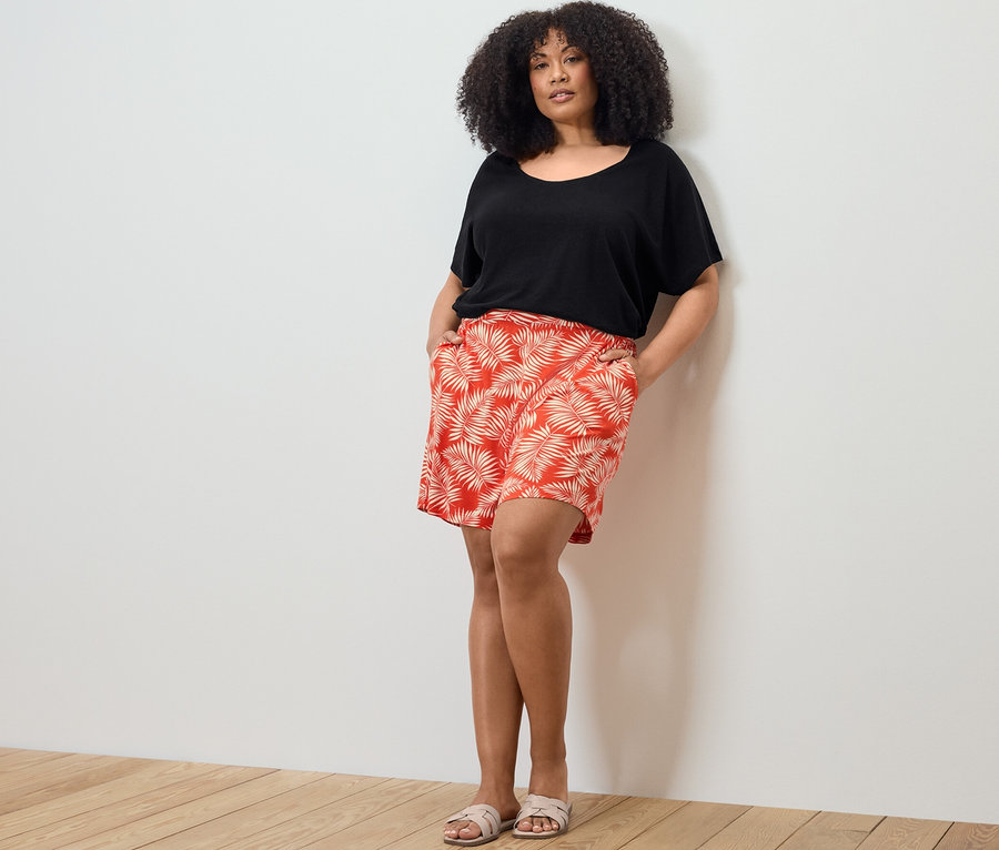 Une femme pose, portant un t-shirt en lin mélangé et un short en jersey imprimé.