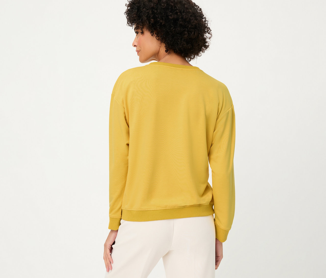 Femme de dos portant un sweat-shirt Olsen manches longues jaune et un pantalon clair.