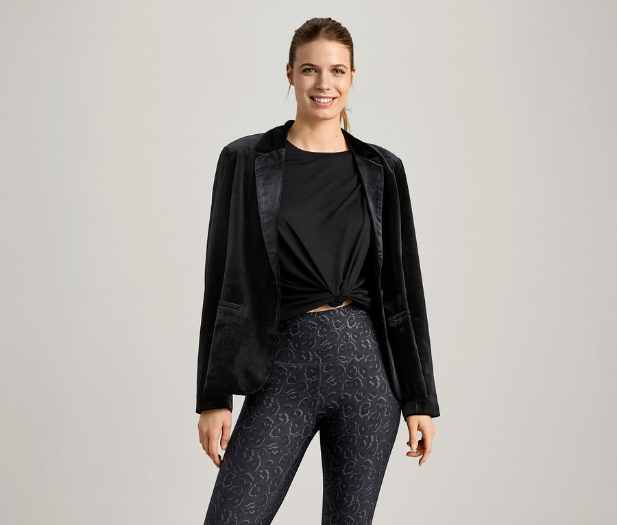 Femme portant un t-shirt de sport noir et un blazer noir.