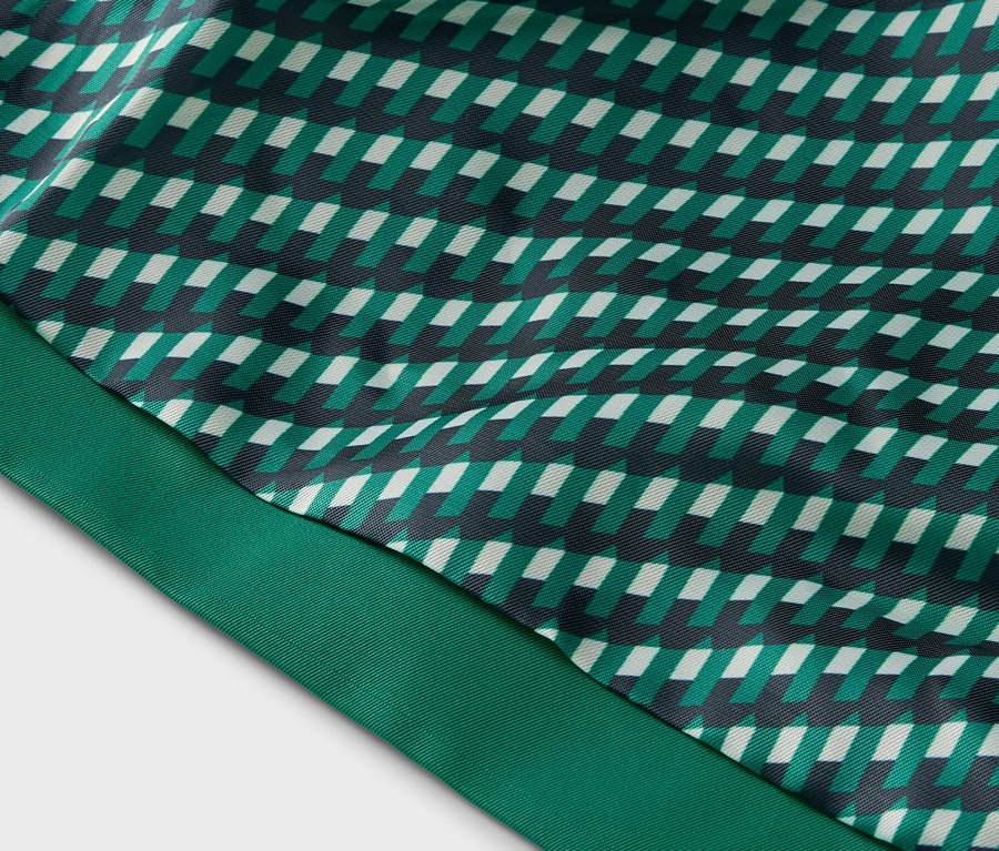 Gros plan d'un tissu à motif géométrique dans les tons de vert, blanc et noir, et d'un ruban vert.