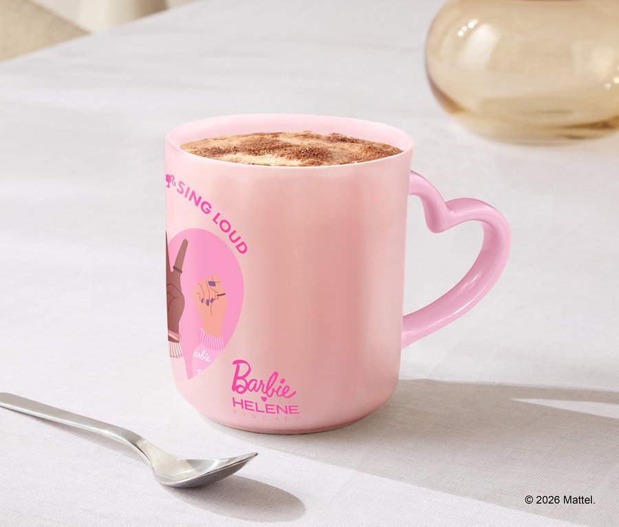 Une tasse rose avec une anse en forme de cœur est posée sur une table à côté d'une cuillère et de biscuits.