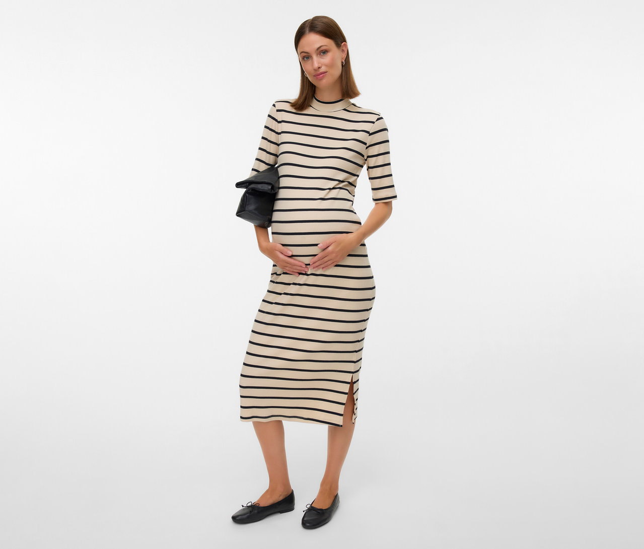 Femme enceinte portant une robe MAMALICIOUS « MLLANE » rayée noire, tenant un sac noir et portant des ballerines noires.